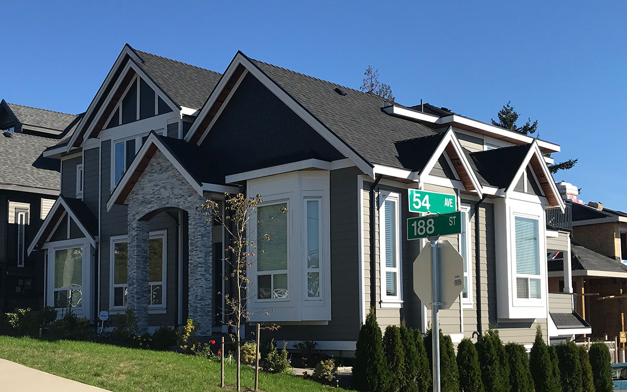 Grey home with stone details and bay windows on a street corner