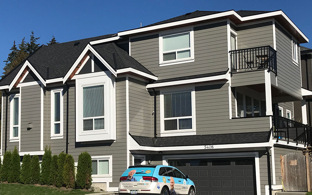 Grey three-storey home with balconies and a garage