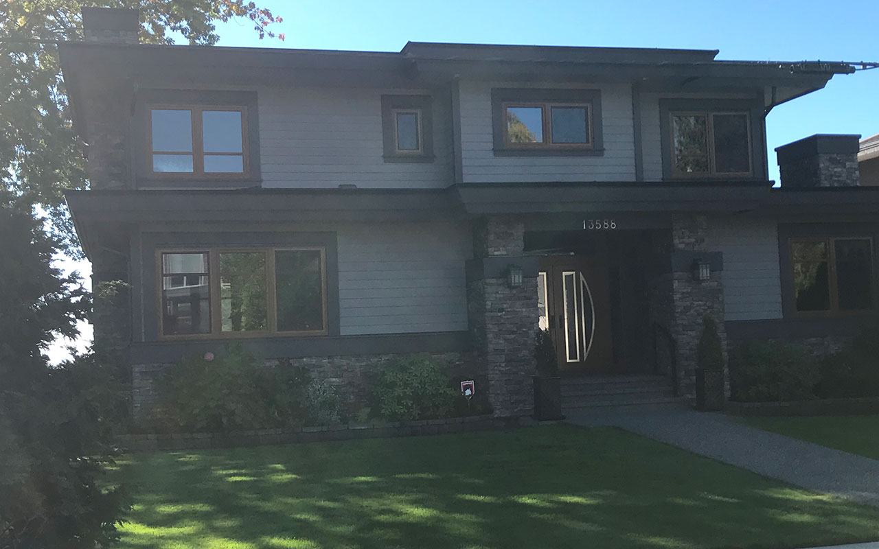 Dark two-storey home with a lawn and large windows